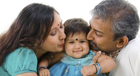 Parents kissing their baby on either cheek